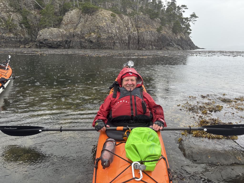 Bob in a kayak on a lake and a rock outcropping