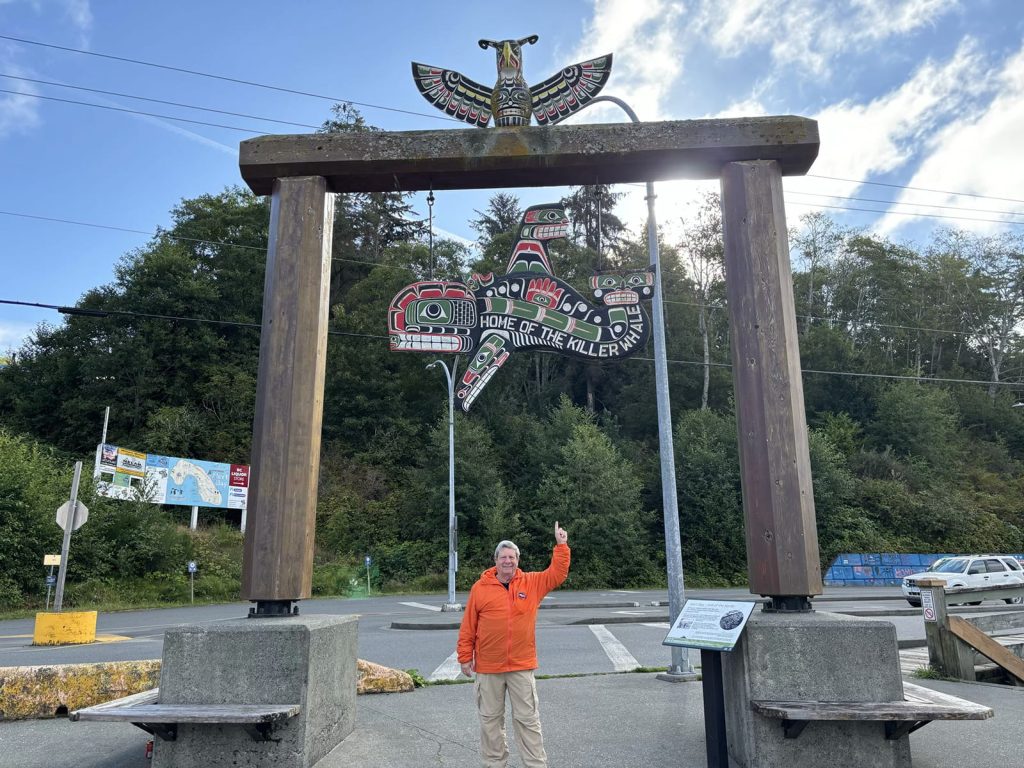 Bob Rein Reflections Off The Grid near colorful totem pole with animal carvings in park forest setting smiling