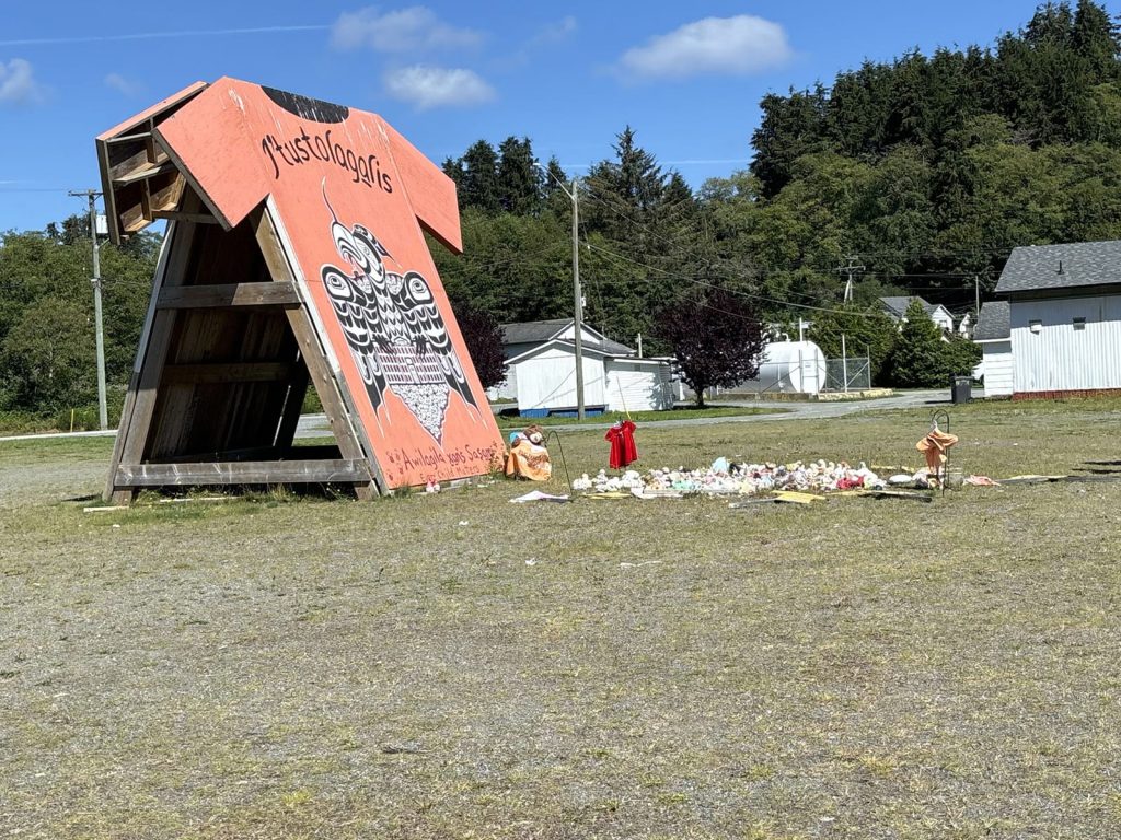 Bob Rein Reflections Off The Grid vibrant orange tee shirt monument with eagle design and scattered debris in rural area with blue sky