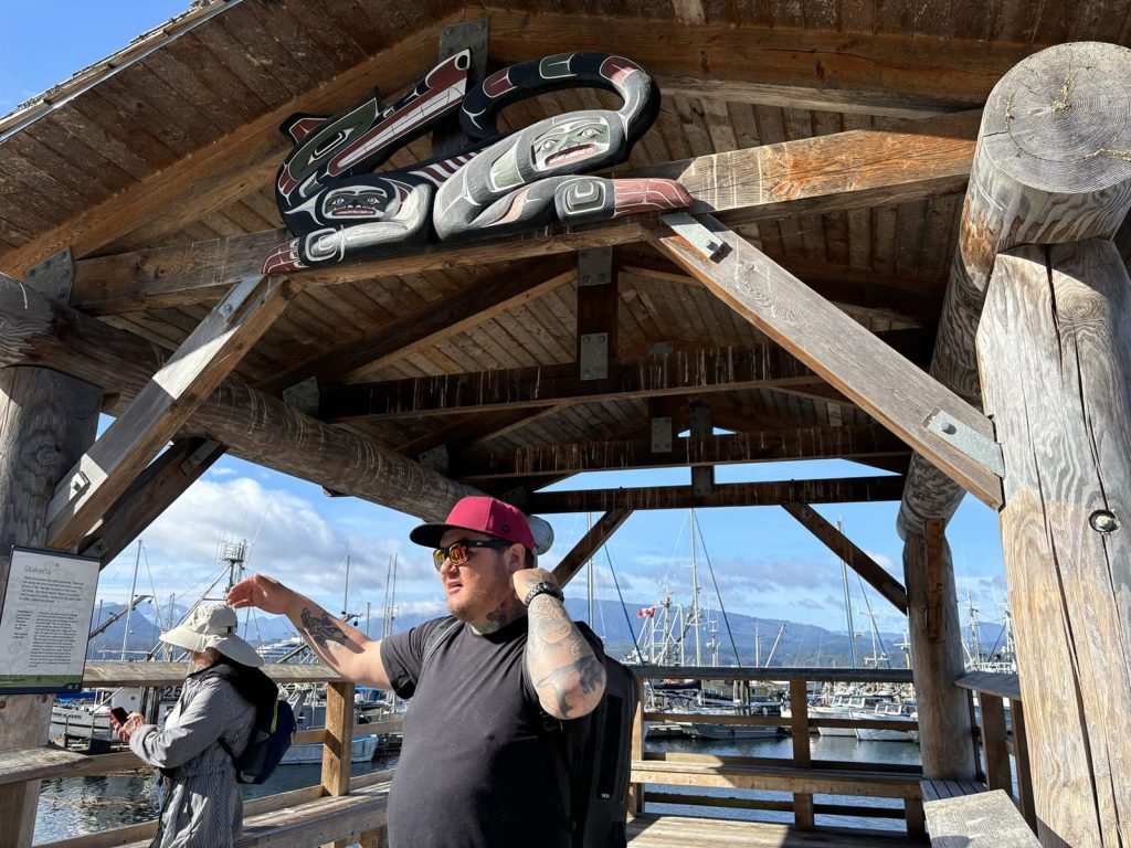 Bob Rein Reflections Off The Grid weathered dock shelter with colorful cat sign and person in black shirt red cap at marina